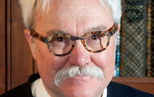 Bill Peak: a white man with white hair and a white mustache, with thick, tortoise-shell glasses.