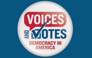 A white round button that looks like a campaign button says "Voices and Votes: Democracy in America." Every letter is capitalized. "Voices" is in white font on a red speech bubble and "Democracy in America" are in red font. "And Votes" is in blue font. The "V" is also a checkmark. The button is in front of a background that matches the blue of the text.