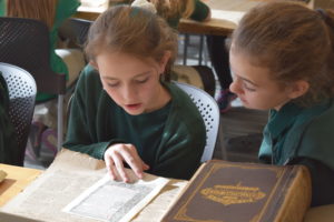 Two young girls look at archival materials