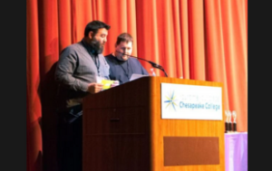 2 large white men at a podium before they present awards to students