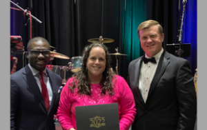 A Black man in a suit, a white woman with brown hair in a sparkly pink top holding a diploma cover that says "2022," and a white man in a tux.