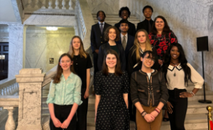 A group of 11 middle and high school students, and one teacher, standing on the steps of the Maryland State House at the Maryland State House in Annapolis.