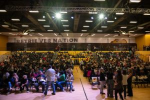 A crowd seated for an awards ceremony in a college activities center/gymnasium.