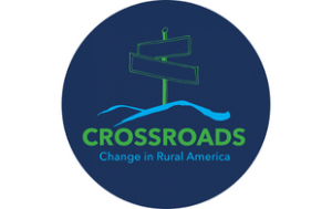 A navy blue circle that says "Crossroads: Change in Rural America." The first word is bright green and the rest are sky blue. Above the text is a signpost on a pole in a matching green, over mountains, outlined in the bright blue.