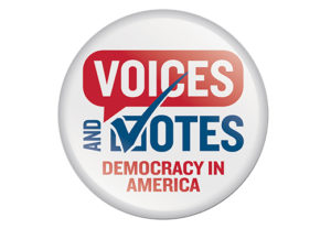 A white round button that looks like a campaign button says "Voices and Votes: Democracy in America." Every letter is capitalized. "Voices" is in white font on a red speech bubble and "Democracy in America" are in red font. "And Votes" is in blue font. The "V" is also a checkmark.